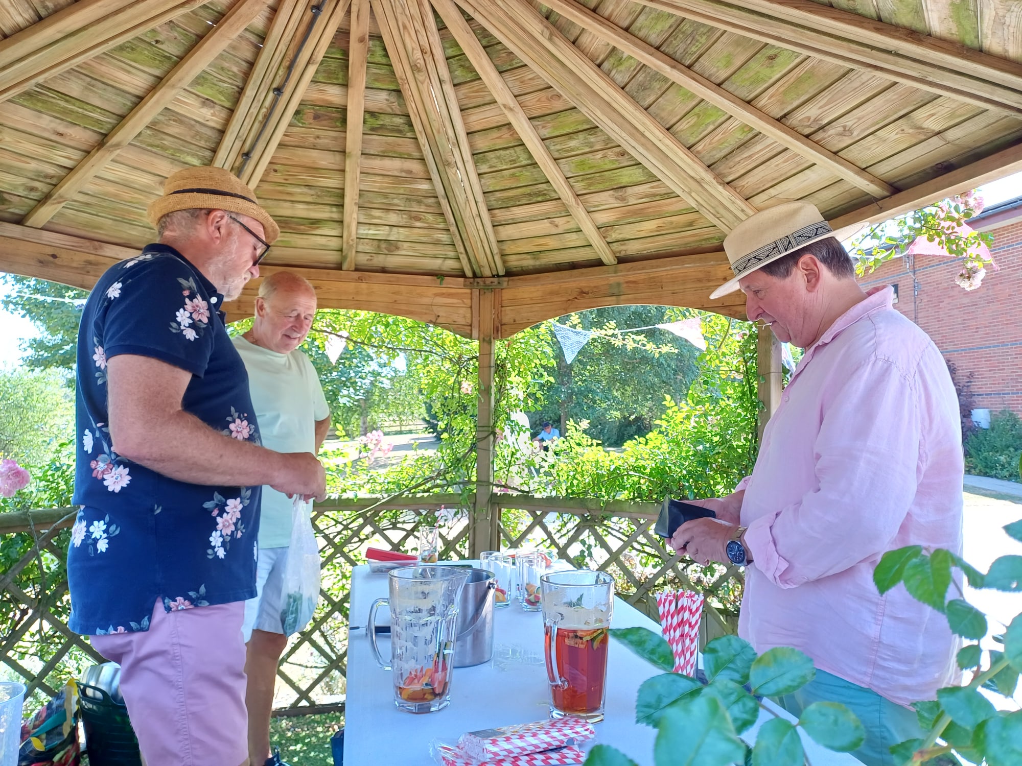 Three people preparing Pimm's drinks under a wooden gazebo at the Summer Show
